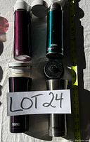 Photo of four Thermos insulated bottles showing colors and lids alongside measuring tape
