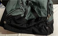 Bottom and side view of the bag showing black base fabric and green upper fabric with zipper and strap details.