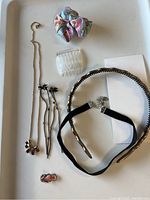 Overview of necklace, earrings, ring, hair comb, headbands, and bow clip arranged on white tray