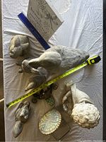 Nine yard animal decorations arranged on a flat surface with measuring tapes for scale. Includes a large goose, sheep, rabbits, and a child's head statue. Visible wear with small chips noted.