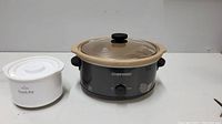 Black Chefman ceramic crockpot with glass lid and knob, along with smaller white Rival dip warmer on the side
