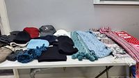 Wide shot showing collection of hats, scarves and mittens on a table