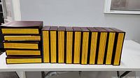 Multiple leather-like bound containers holding National Geographic magazines arranged on a white table.