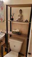 Shelving unit fitted over toilet with decorative items on shelves