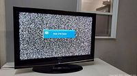 Samsung TV screen displaying static and a 'Watch on the Signal' message, showing the TV is powered on and screen active.
