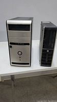 Photo of two computer towers on a white table, one large beige and one small black mini-tower.