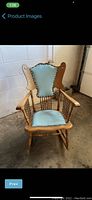 Photo showing antique oak rocking chair with teal upholstery and decorative brass tacks on seat and backrest, spindle arm supports and turned legs with rockers.