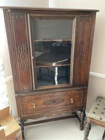 Front view of antique wooden china cabinet with carved details and glass door