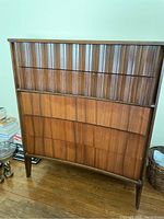 Front view of tall wooden dresser showing vertical decorative panels and tapered legs