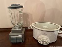 Photo of two small kitchen appliances: a Cuisinart blender with glass pitcher and a Rival Crock-Pot slow cooker with a white body.