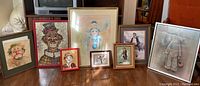 Overview photo showing all eight framed clown art prints arranged on floor in front of a mirror and cabinet