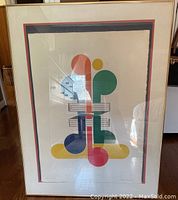 Photo of abstract print with colorful musical notes and geometric shapes behind glass with white matting and frame