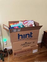 Wide view of large cardboard box filled with various gift bags and wrapping supplies.