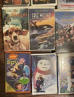 Photo showing a group of six VHS tapes: Shiloh, Free Willy 2, Richie Rich, Harriet the Spy, Jack Frost, and another VHS tape partially visible.