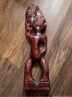 Front view of the wooden carved figure showing detailed spiral patterns and large expressive eyes with inlays.