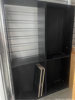 Black entertainment center or shelving unit with multiple compartments and detachable shelves.
