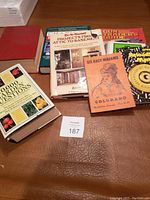 Books on a table including variety of genres, gardening, home improvement, and true crime.