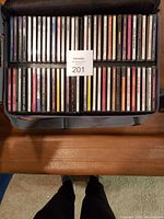 Top view of a carrying case filled with music CDs stacked in two rows, showing a variety of album spines.