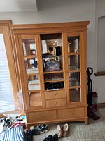 Front view of China hutch showing glass doors, central open shelving with drawers, and lower drawer.