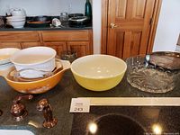 Photo showing a variety of cooking and serving dishes including glass and Pyrex bowls and casserole dishes on a black countertop.