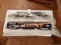 Navy blue and orange metal passenger dome car with stylized “VICTORY” lettering, Broncos logos and player images seated in original foam tray