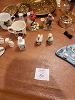 Close-up photo focusing on detailed view of brass trays, bird figurines, salt and pepper shakers, mugs, and bell
