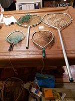 Four fishing nets laid flat on a brown surface showing various sizes and styles.
