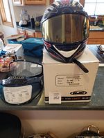 Helmet displayed on top of the original box showing front view with helmet box label indicating model CL-14S, size Large, color Fuse MC1.
