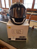 Front view of HJC motorcycle helmet on box, showing clear visor and helmet shape