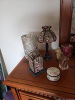 Mosaic glass vase and lamp with stained glass flower design on wooden surface