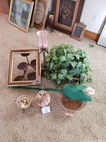 Lot containing gold frame, metal candle holder, baskets with artificial flowers, and jars with dried decor on carpet