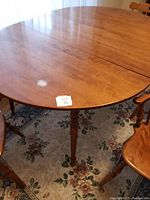 Oval dining table top showing wood grain, sheen, and central seam for leaf insertion.
