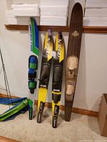 Photo showing two yellow and black Obrien water skis and one wooden Solemn water ski.