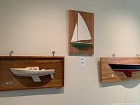 Overview of three mounted half-hull boat models on wall