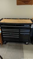 Full view of black Craftsman tool cabinet on wheels with nine drawers and plywood top
