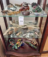 Entire display cabinet showing collection of decorative lizard figurines on three shelves