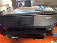 Black HP Envy 5660 printer shown from front with display screen.