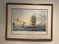 Framed lithograph showing tall sailing ship at sea near shore