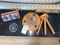 Overview of kaleidoscope tube, stand, wooden holder and one loose wheel on black surface