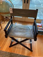 Front view showing green leather seat and backrest on black wood frame.