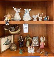 Full shelf view showing two Lladro porcelain angels in the center top shelf among other angel figurines and a copper angel sculpture below.
