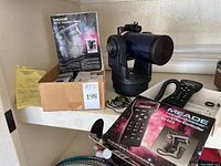 Overview of telescope, controller box, accessory catalog and box of items on shelf