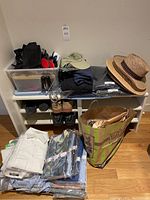 Overview: white shoe bench with folded shirts, hats on top, bin containing gloves, suspenders, lint brushes and tie holders, shoes on rack