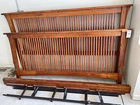 Headboard and footboard leaning against wall with side rails in front