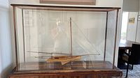 Front view of entire glass display case showing wood-framed enclosure housing the model yacht