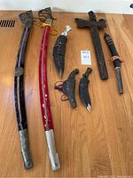 Overall overhead view of all six edged weapons arranged on wood floor