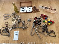 Overview of assorted brain teaser puzzles arranged on wooden floor including metal wire puzzles, wooden puzzles with colored balls and tangram