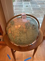 Full view of illuminated globe on wood tripod stand