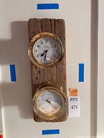 Full front view of wood plank with two brass instruments mounted.