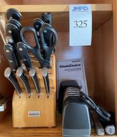 Wüsthof knife block with multiple knives and kitchen scissors alongside Chef's Choice Hybrid Diamond Hone sharpener with user manual.